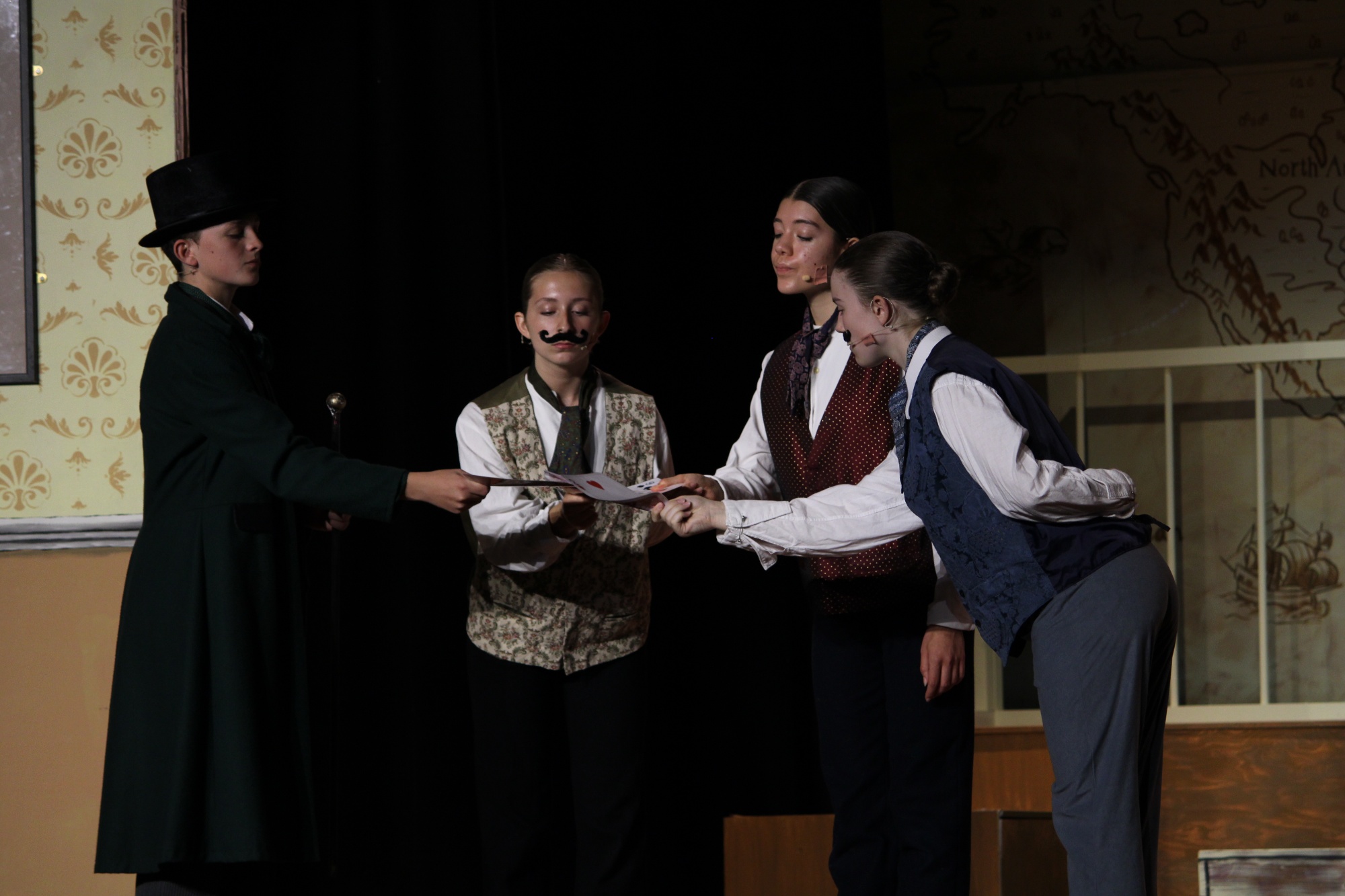 Image shows 4 male characters from the play chatting