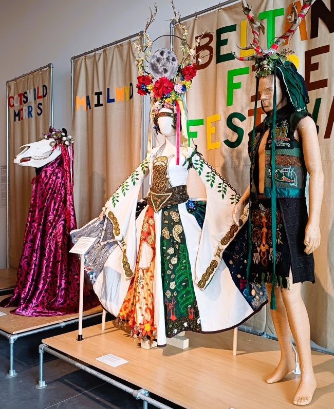 Image shows a display of 3 colourful Morris dance costumes representing spring and summer