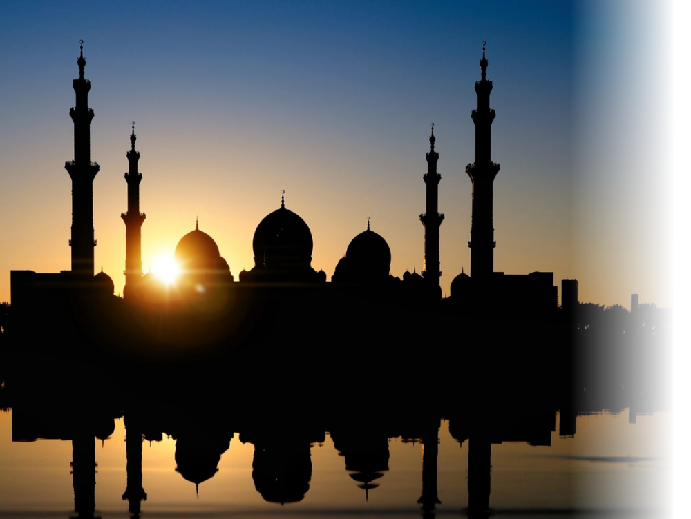 Image shows a Sheikh Zayed Grand Mosque in Abu Dhabi with a low sun behind it, reflected on the water in front of it